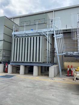 Industrial cooling tower fitted with a metal access platform and ladder, providing safe access for inspection, cleaning, and mechanical servicing.