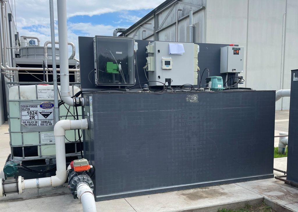 Above-ground wastewater treatment system with controller-based automatic chemical dosing and an IBC chemical tank used to manage wastewater pH and discharge compliance.